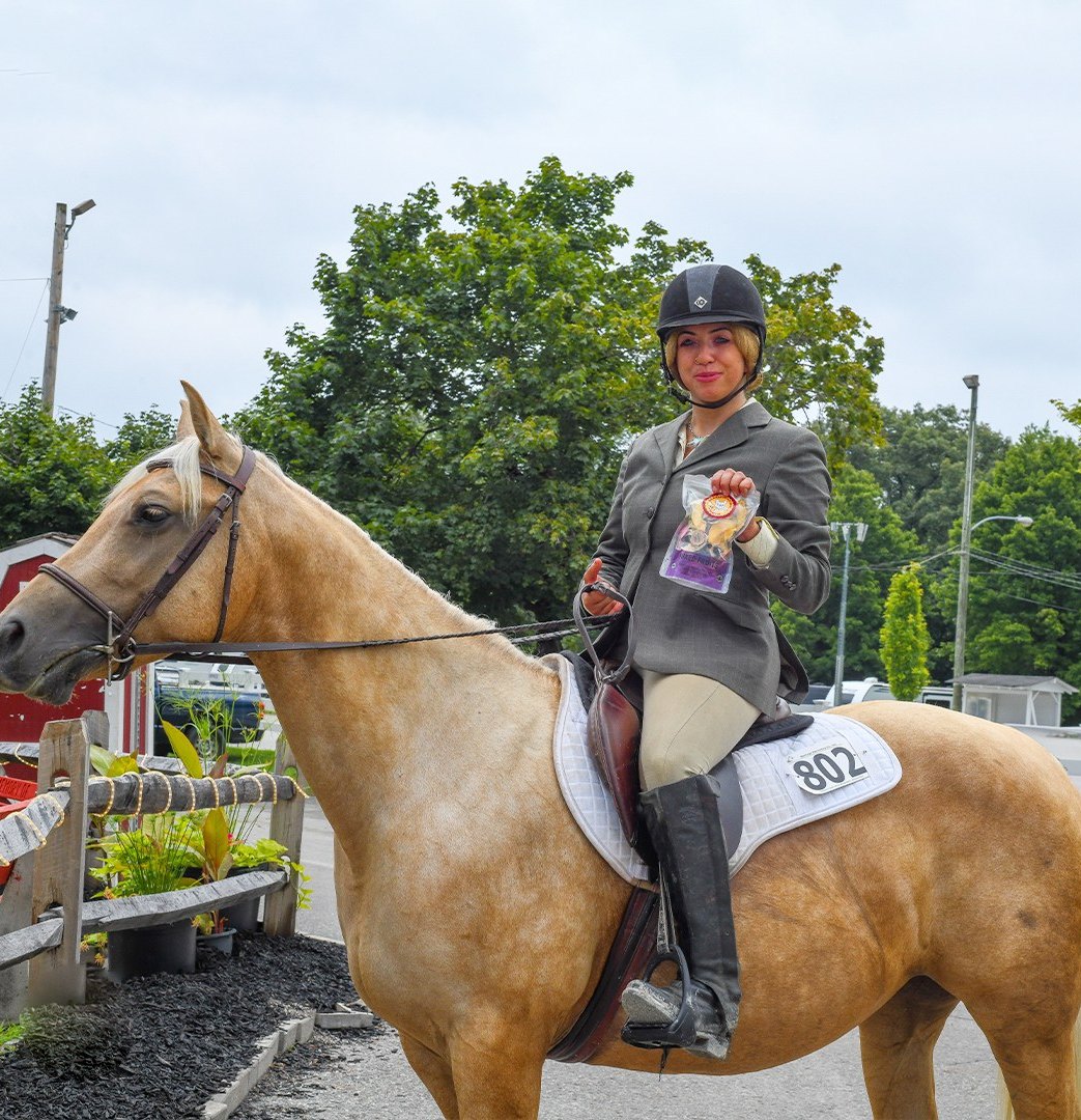 Rider on a palomino horse holding Gratification Pets Mixed Fruits